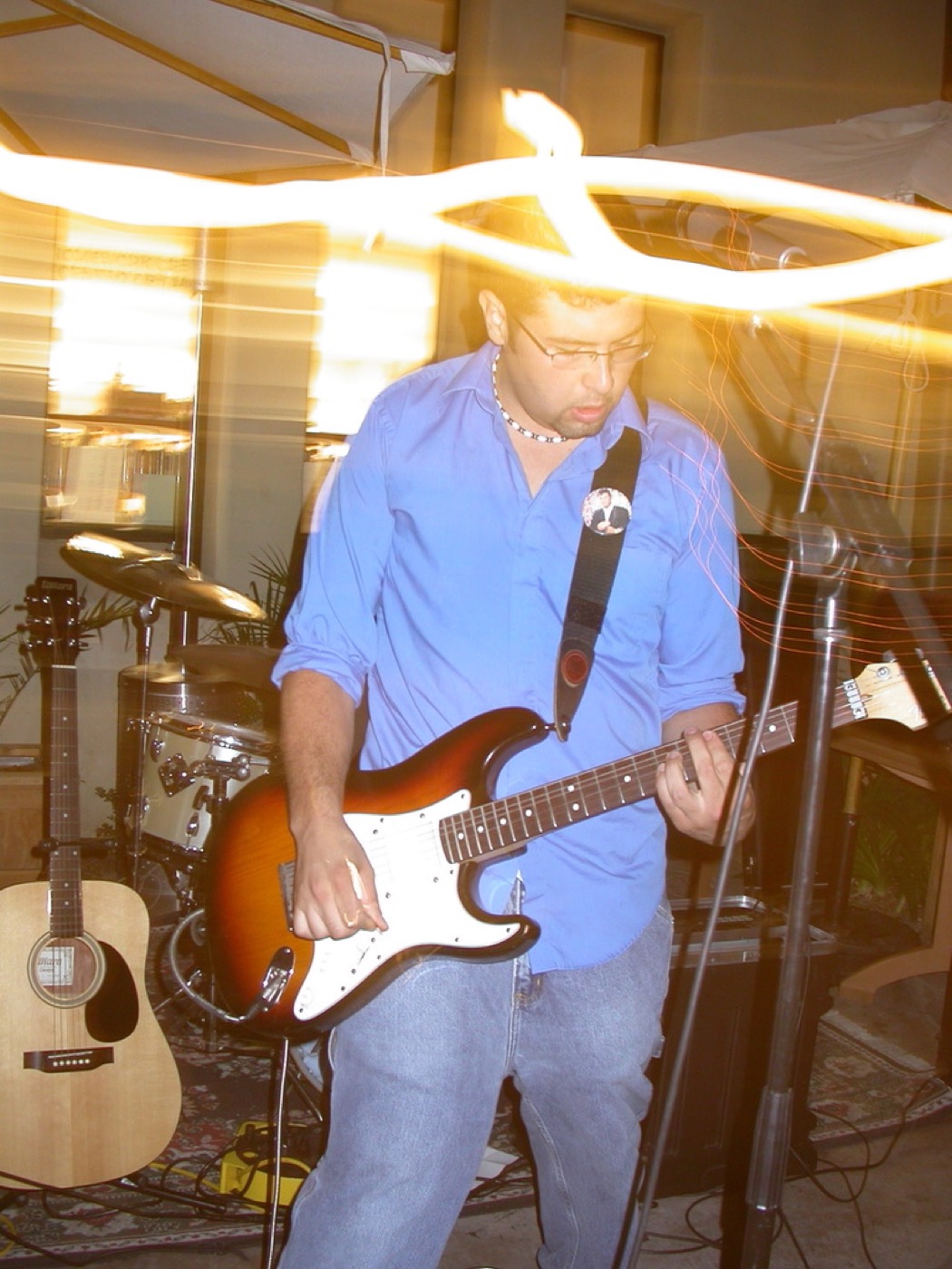 Eddie Garcia performing guitar live in a blue shirt with stage lights.