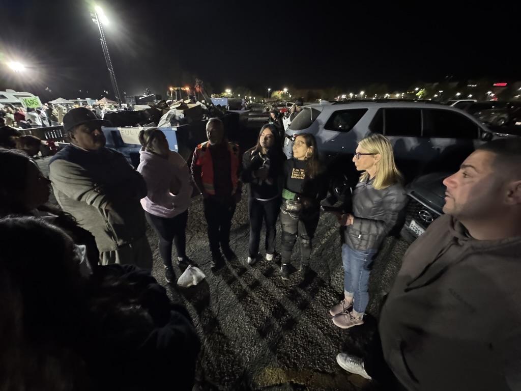 A small group standing in a circle at night coordinating next steps at the relief effort.
