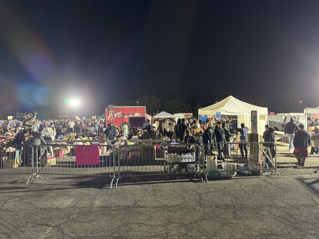 Nighttime scene at the Santa Anita relief hub with tents, supplies, and people coordinating aid.